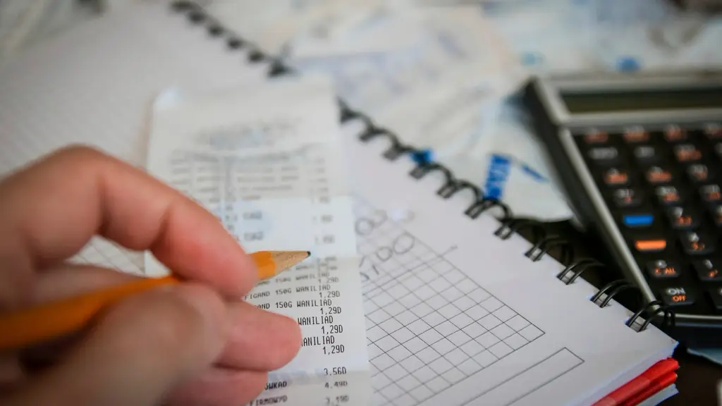 Hand checking receipts beside a calculator
